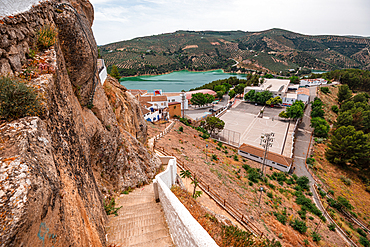 Izn&aacute;jar, C&oacute;rdoba, Andalusia, Spain. A path beneath rugged cliffs leading to whitewashed houses above the reservoir. Pueblo blanco and dramatic Andalusian landscape.