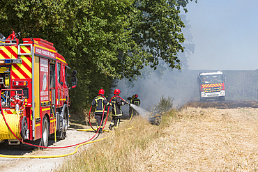 Firefighters combat stubble fire in harvested field during summer in Centre-Val-de-Loire region of France