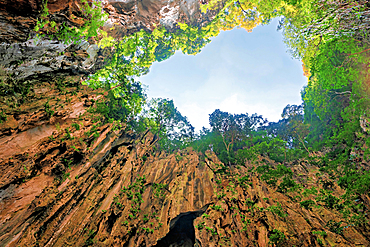 Visiting the main cave of Batu Caves in Selangor, Malaysia during daylight hours with greenery and rock formations above<br />1390-1293 Visiting the main cave of Batu Caves in Selangor, Malaysia during daylight hours with greenery and rock formations above