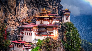 Buddhist monastery nestled on a cliff side in Bhutan, surrounded by mountains and forest