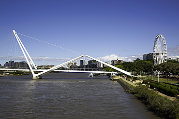 Bridge spans across the Brisbane River with city skyline and park in view during daylight in Brisbane, Queensland, Australia
