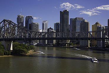 Ferry travels along the Brisbane River under the Story Bridge with the city skyline in the background in Brisbane Queensland Australia