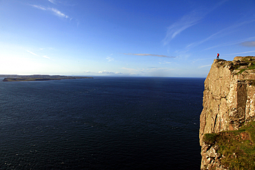 Hiker looks out to Rathlin Island, Fair Head, Northern Ireland