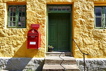 Post office, fa&ccedil;ade detail, red mailbox with post horn and crown, green wooden door, yellow wall, Christians&oslash;, Christians&ouml;, Ertholmene, Pea Islands, Bornholm, Baltic Sea, Denmark