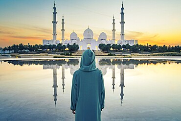 Close up Woman in traditional Arabic dress Abaya in Wahat Al Karama or Oasis of Dignity near Sheikh Zayed Grand Mosque in Abu Dhabi, showcasing cultural elegance, iconic Islamic architecture at sunset