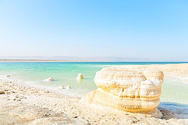 Dead Sea salt crystal formations on shoreline beach in Jordan on sunny mid-day with turquoise water desert coast. Lowest point on Earth landscape. Jordan - Israel border line zone