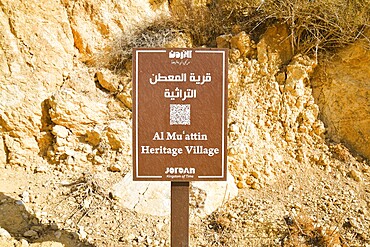 Al Muattin, Jordan - 6th december, 2025: Al Muattin Heritage Village Official Tourist Informational Signboard In Jordan. Brown public notice board with white text and QR code indicating entrance