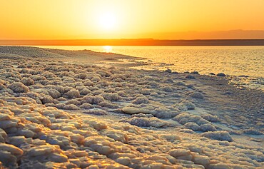 Close up Dead Sea salt crystals on shoreline beach in Jordan at sunset with turquoise water desert coast lowest point on Earth landscape. Jordan - Israel border line zone