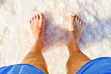 Close-up POV male tourist walking on the unique salt formations and turquoise mineral-rich waters of the Dead Sea beach. A concept for wellness, healthy living, and natural spa travel