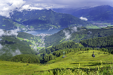 View of Zell am See from Schmittenhohebahn top station on a sunny day with clouds in the sky and greenery below