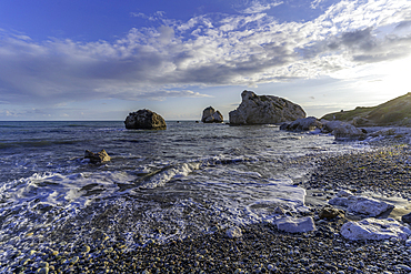 View of Aphrodites Rock and beach with clear skies and gentle waves at Petra tou Romiou in Cyprus on a sunny day