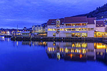 Buildings around Bergen Harbour at dusk reflect on the water in the city of Bergen, Vestland, Norway
