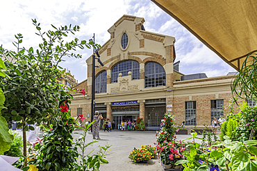 View of Mercado Central de Alicante on a sunny day with people and flowers outside the entrance<br />844-48565 View of Mercado Central de Alicante on a sunny day with people and flowers outside the entrance