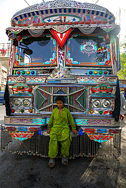 Colorful bus with decorations and a child sitting at Empress Market in Karachi, Pakistan during daylight