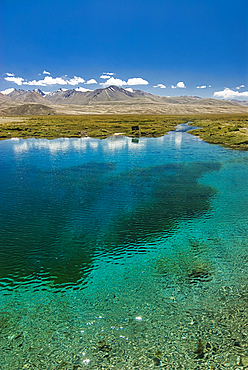 Turquoise spring Ak Balyk reveals clear waters beneath a wide sky in Pamir region of Tajikistan