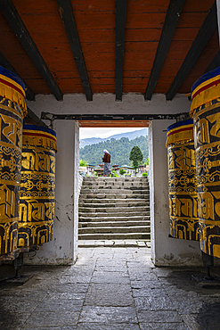 Exploring the entrance of Chorten Kora monastery in Trashiyangtse, Bhutan, with prayer wheels in view<br />1184-19217 Exploring the entrance of Chorten Kora monastery in Trashiyangtse, Bhutan, with prayer wheels in view