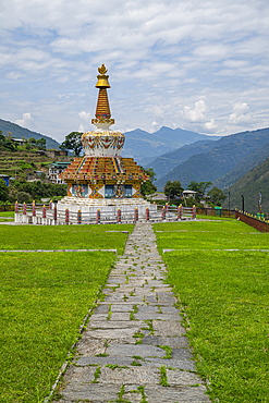 Stupa located in Trashigang, Bhutan stands prominently among green fields and mountains under a cloudy sky