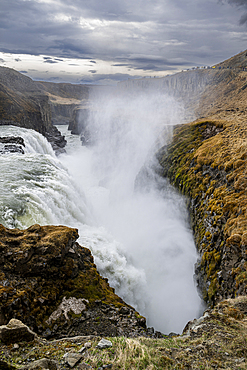 Gullfoss waterfall in Iceland showing water flowing over rocks with mist rising