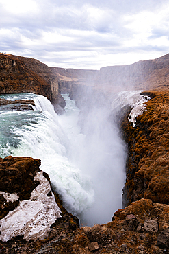 Gullfoss, Golden Circle, South Iceland. Gullfoss surging through a narrow basalt gorge in a powerful torrent of glacial water. Iconic waterfall, raw power and dramatic unspoiled scenery on the Hv&iacute;t&aacute; river