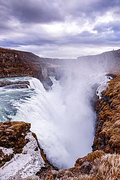 Gullfoss, Golden Circle, South Iceland. Gullfoss plunging into its deep gorge in a powerful column of white water framed by rocky cliffs. Iconic waterfall, raw power and dramatic unspoiled scenery on the glacial Hv&iacute;t&aacute; river.
