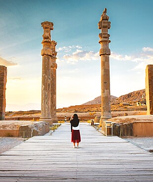 Persepolis ancient - persian city in south Iran. Famous travel destination in middle east. Tourist exploring Persepolis Gate of All Nations ancient stone pillars at sunset in Shiraz Iran UNESCO site