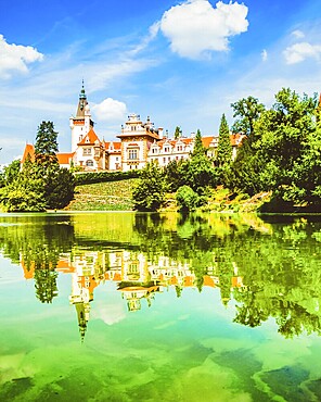 Pruhonice Castle near Prague reflected in lake with lush summer nature. UNESCO heritage site and popular cultural travel destination in Czech Republic