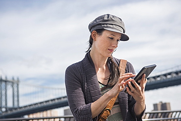 Woman using tablet pc, Manhattan Bridge in background, Brooklyn, New York