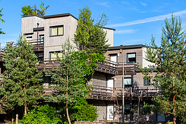 A contemporary residential complex featuring multi-story wooden townhouses with balconies and surrounded by lush greenery at Center Parcs Villages Nature Paris, France.