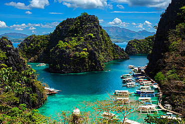 Exploring the clear waters and rocky formations of Coron Island in Palawan with boats anchored in a harbor view