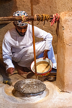 Flour milling process in a traditional setting performed by a man in Oman
