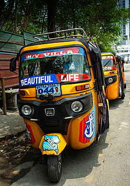 Trishaw taxis parked along the road in Manila with colorful designs and signs during the day